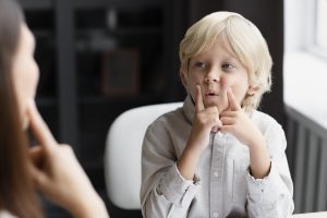 young woman doing speech therapy with little boy young woman doing speech therapy with little boy